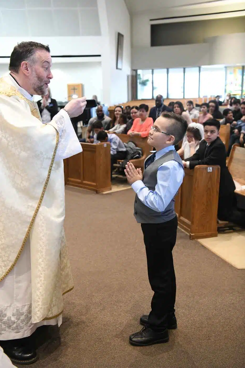 Young boy receiving first communion from priest