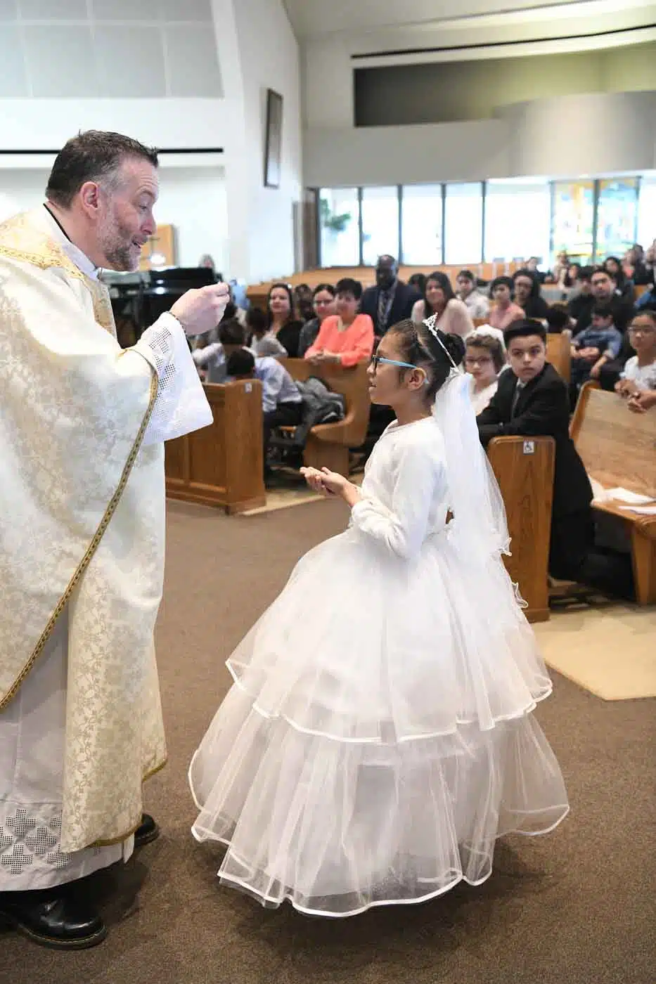 Young girl receiving first communion from priest