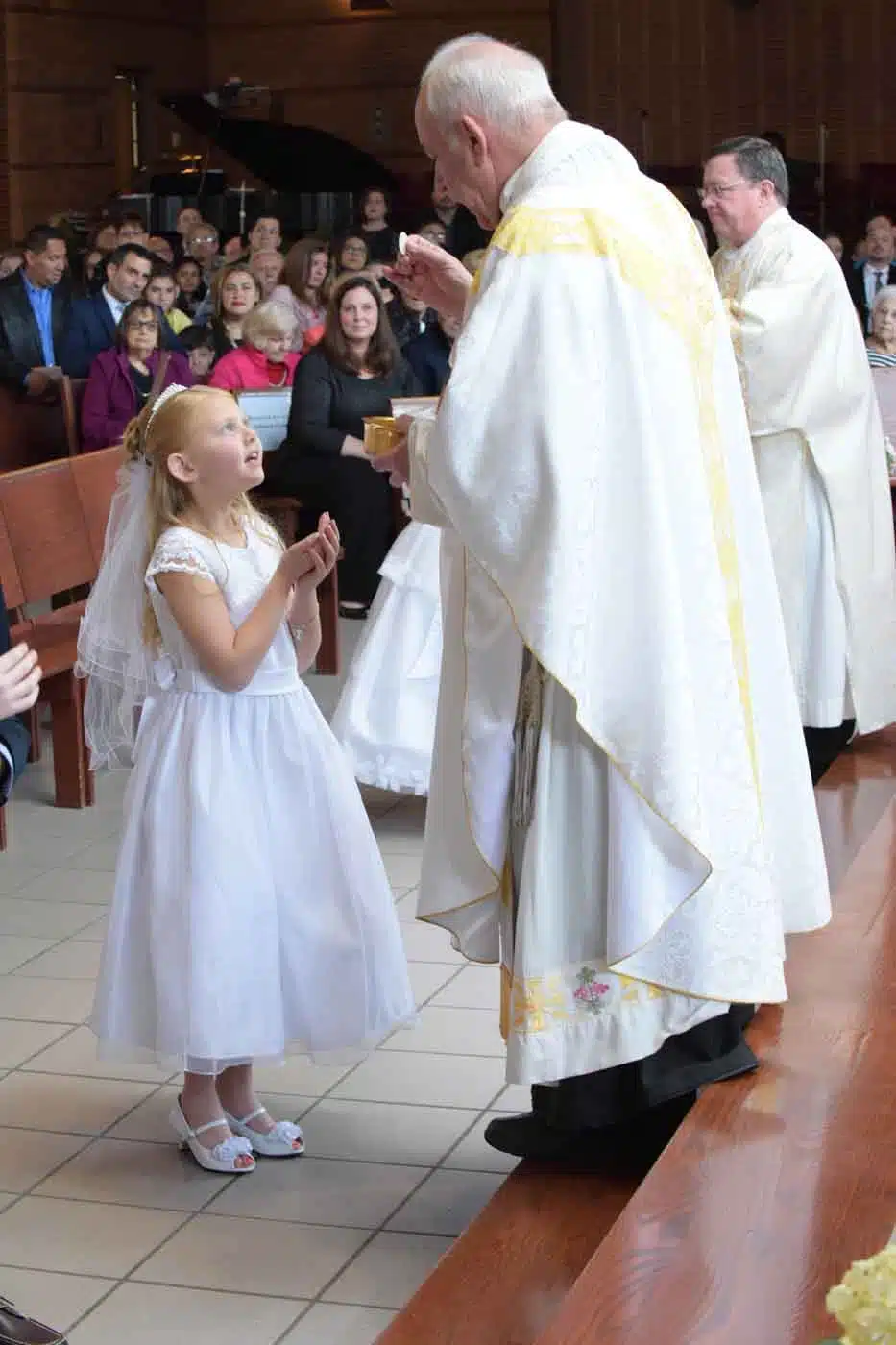 Young girl receiving first communion from priest