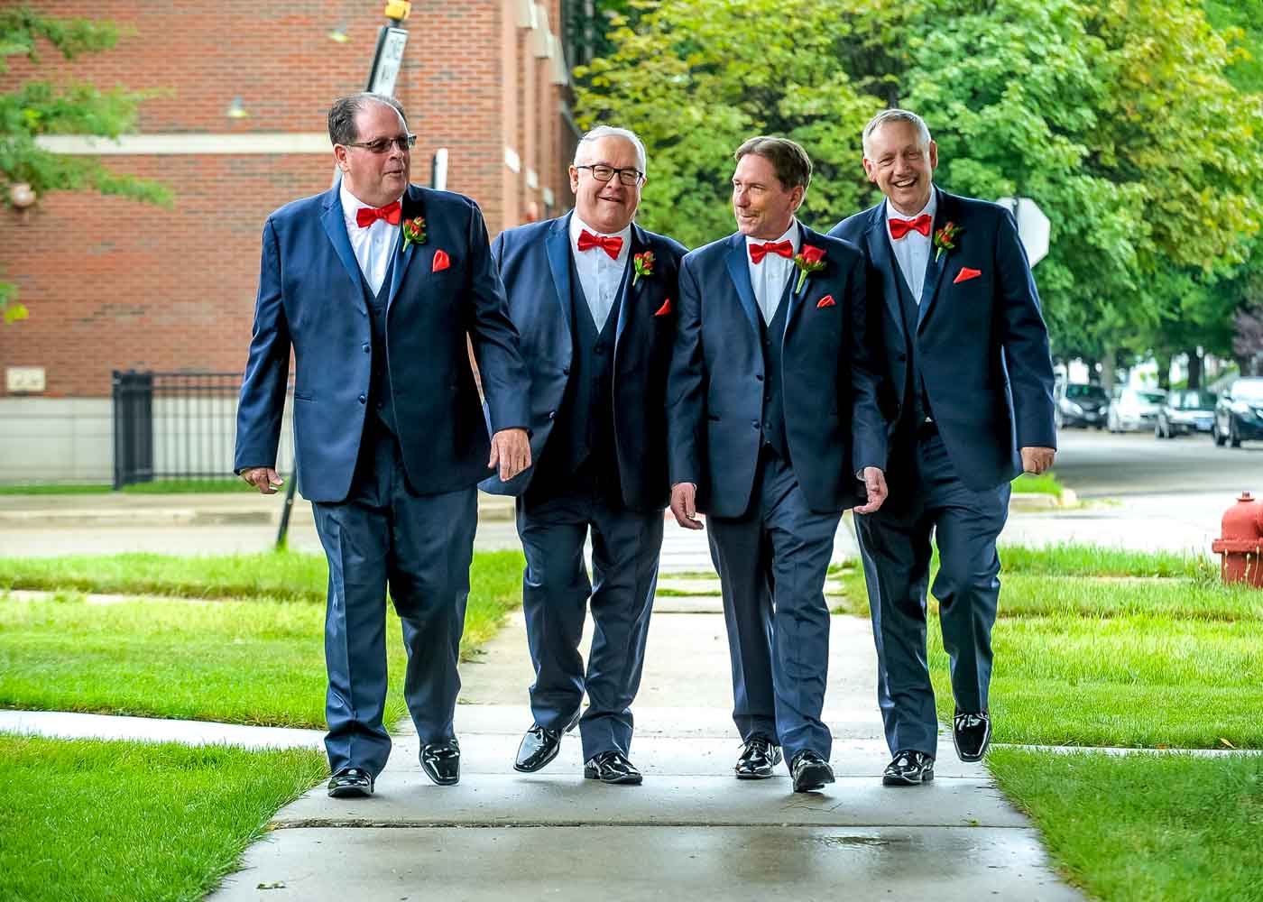 Groom and 3 groomsmen walking on wet sidewalk